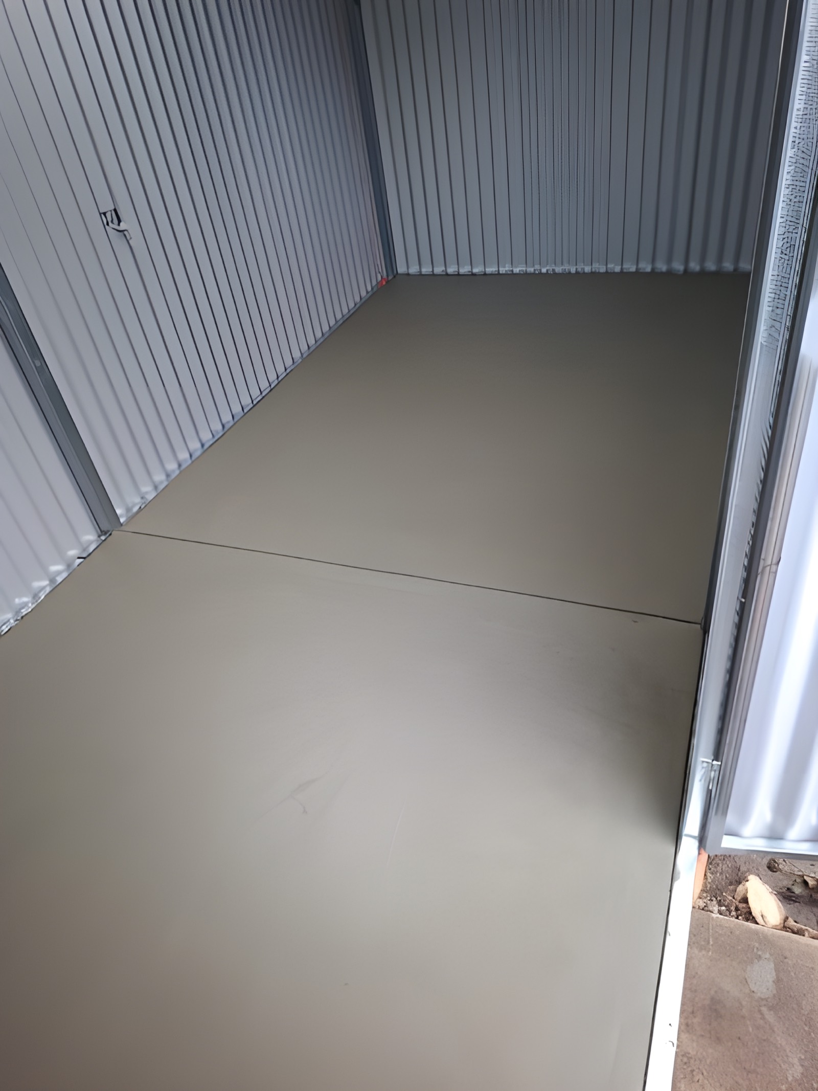 Smooth-finished concrete slab in a narrow side passage between sheds
